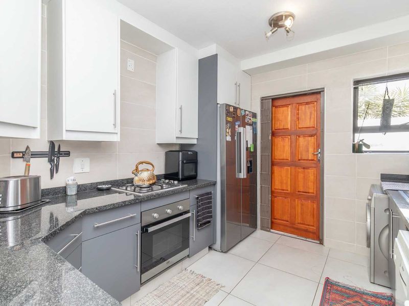 A functional kitchen featuring granite countertops, built-in cabinetry, a gas hob, an oven, and tiled finishes, providing a practical workspace.