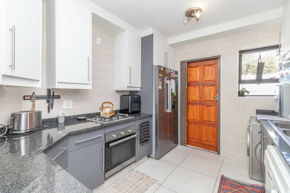 A functional kitchen featuring granite countertops, built-in cabinetry, a gas hob, an oven, and tiled finishes, providing a practical workspace.