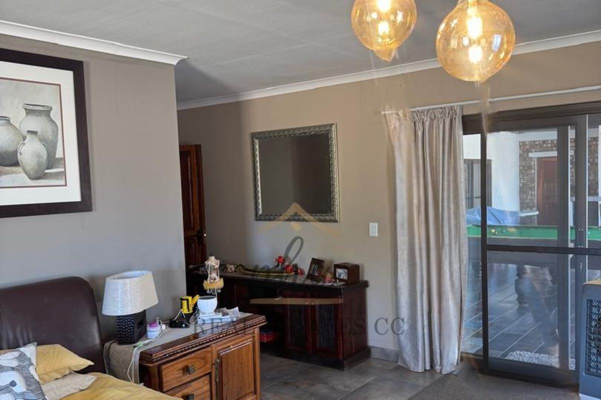 Spacious bedroom featuring tiled flooring, modern pendant lighting, and a sliding glass door providing access to the outdoor patio area.