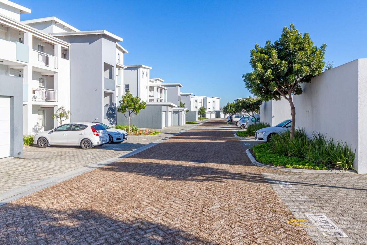 A view of the apartment complex street and driveway, featuring modern building facades, paved surfaces, and landscaped areas.
