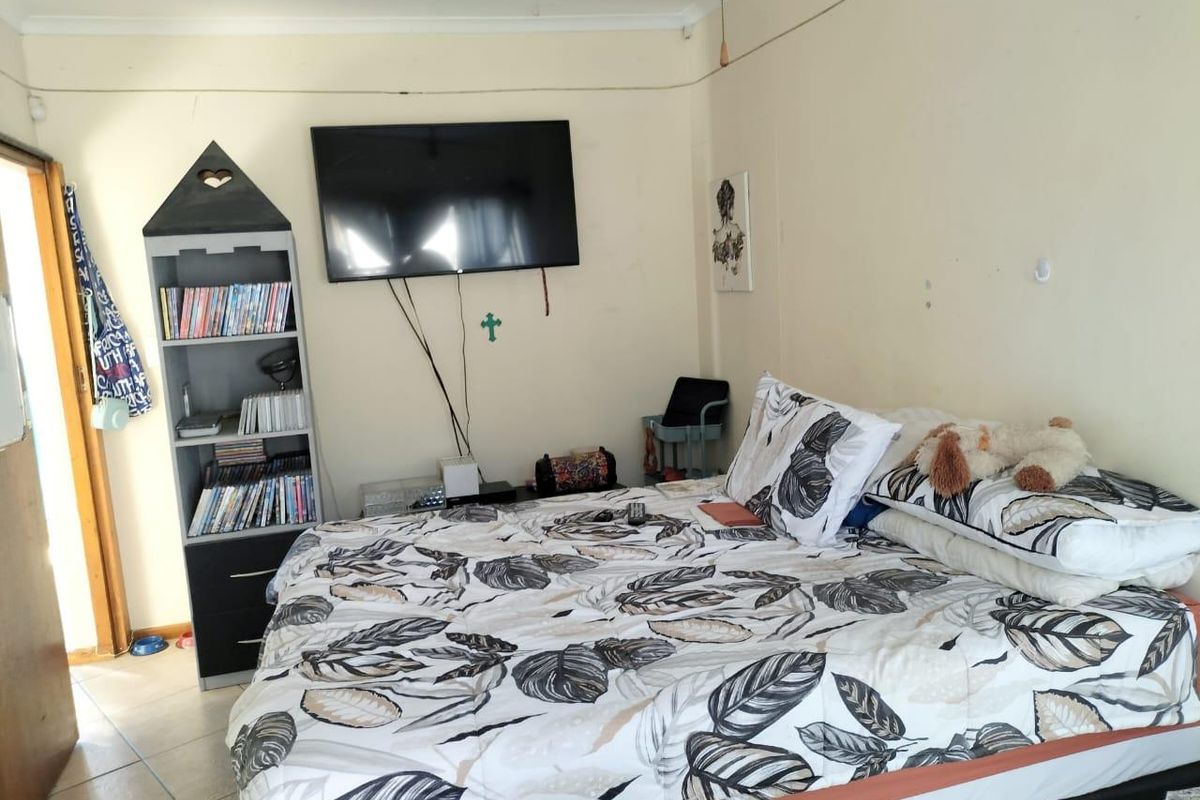 A bedroom featuring tiled flooring and wall-mounted television, requiring minor cosmetic updates to improve the overall finish.