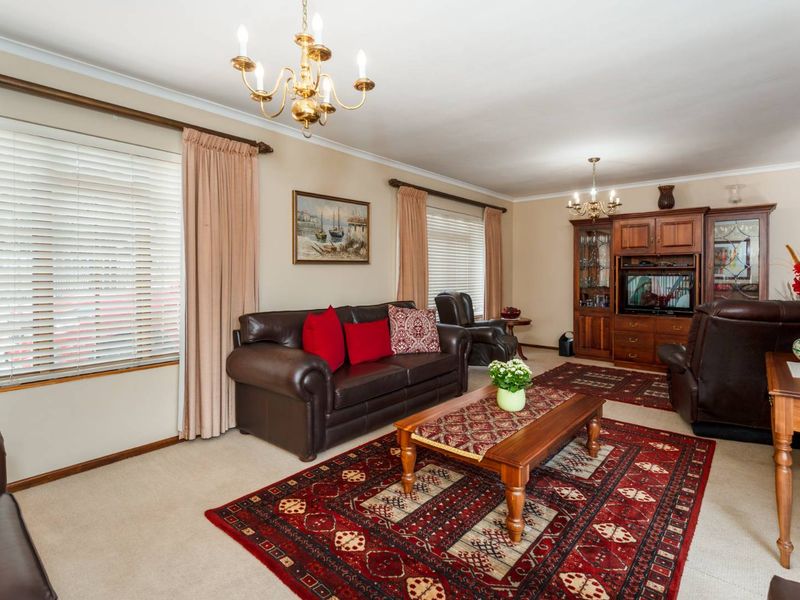 A spacious living room featuring neutral carpeting, classic coving, and built-in wooden cabinetry, offering a comfortable and traditional living environment.