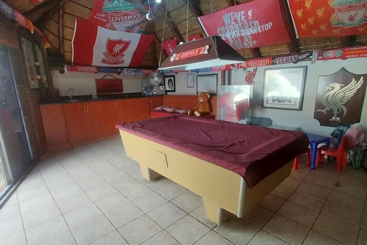 A spacious entertainment room featuring a thatched roof, tiled flooring, and a built-in kitchenette area.