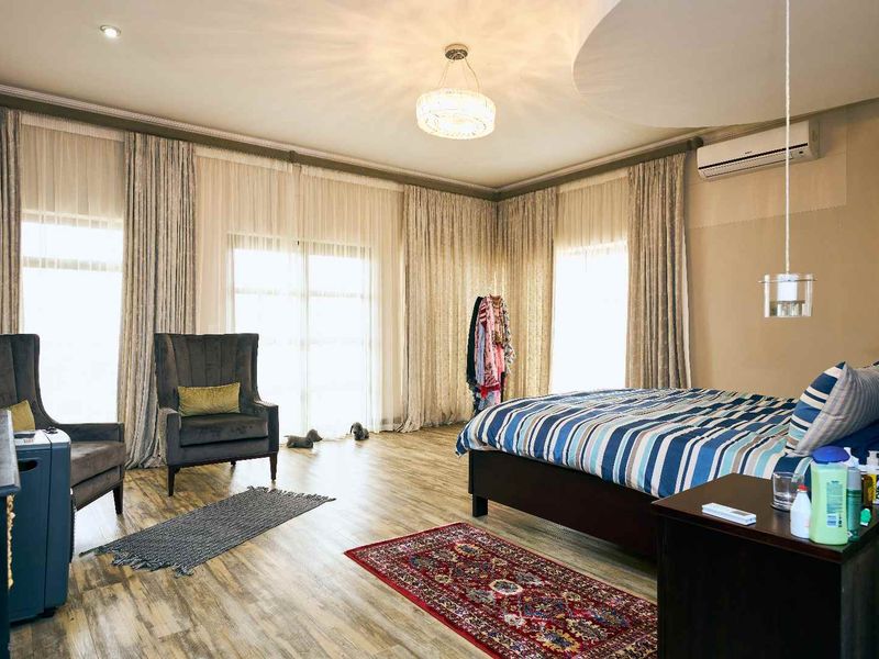 Spacious bedroom featuring laminate flooring, recessed ceiling detail, and large sliding glass doors providing ample natural light.