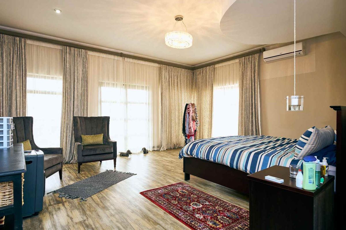 Spacious bedroom featuring laminate flooring, recessed ceiling detail, and large sliding glass doors providing ample natural light.