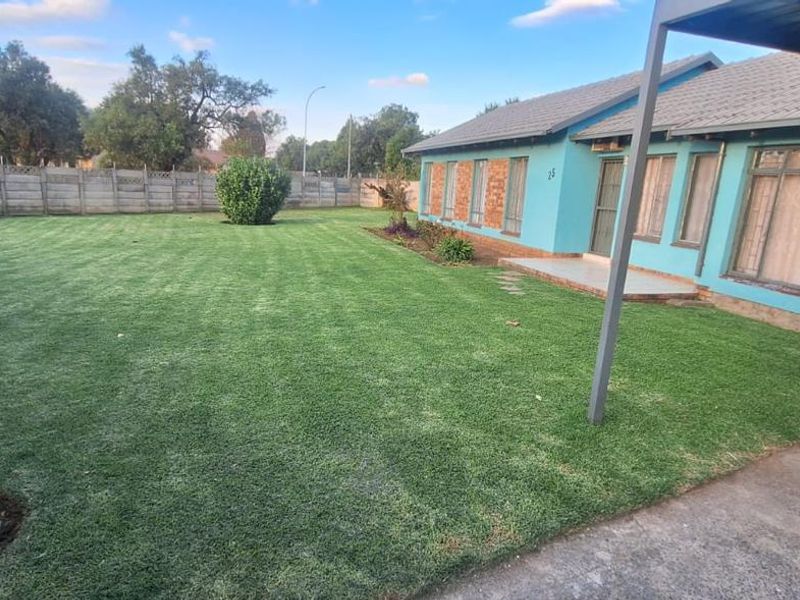 Spacious rear garden featuring a well-maintained lawn, concrete patio area, and secure boundary walling, providing a private outdoor space.