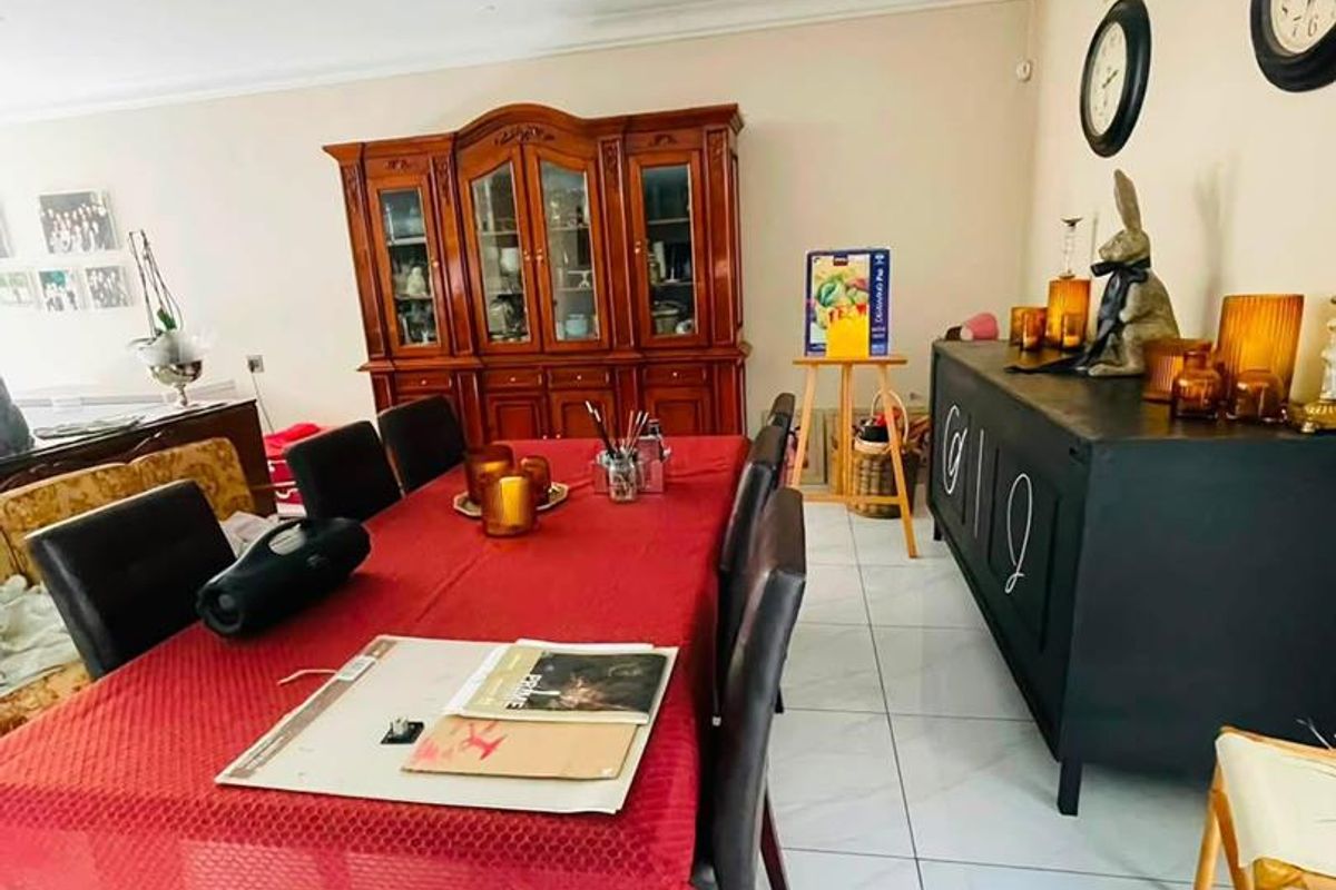 A spacious dining room featuring polished tiled flooring, recessed downlighting, and decorative coved cornicing, providing a neutral foundation for formal dining.