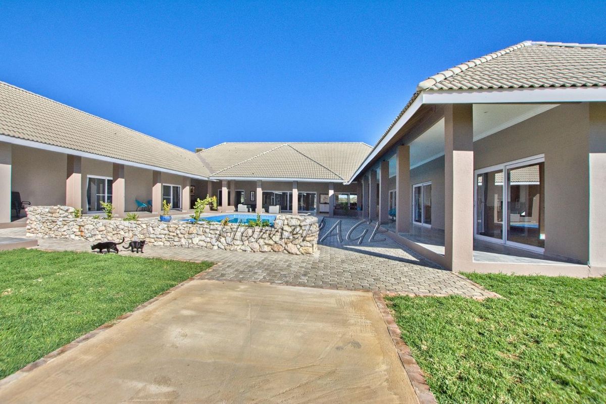 Spacious rear courtyard featuring a swimming pool, paved patio area, and covered walkways connecting the various wings of the property.
