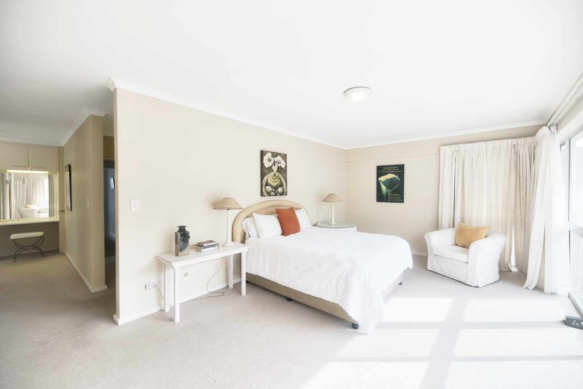 Spacious bedroom featuring neutral carpeting, a built-in vanity area, and large sliding glass doors providing natural light.