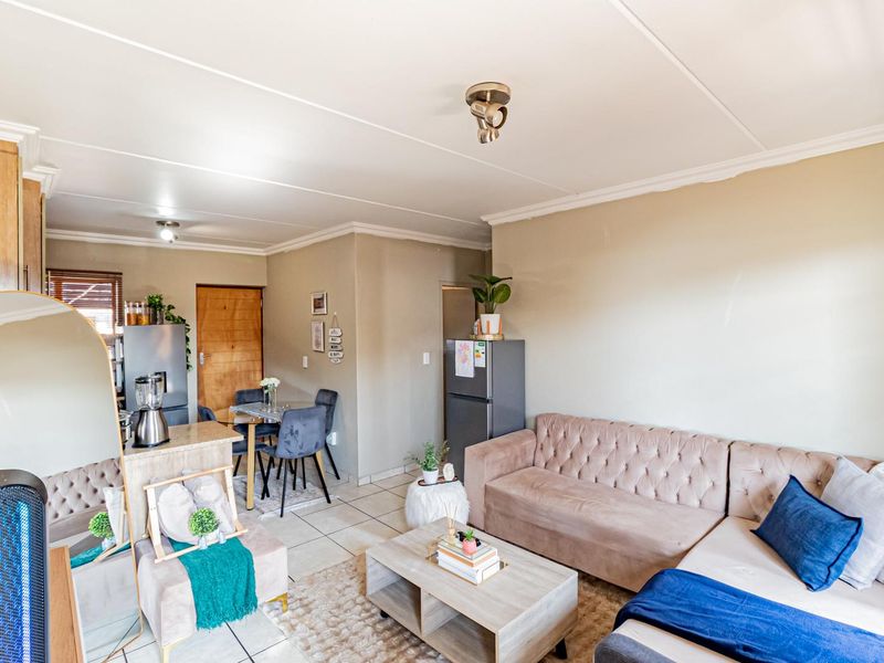 An open-plan living and kitchen area featuring tiled flooring and neutral wall tones, providing a functional and connected space for daily living.