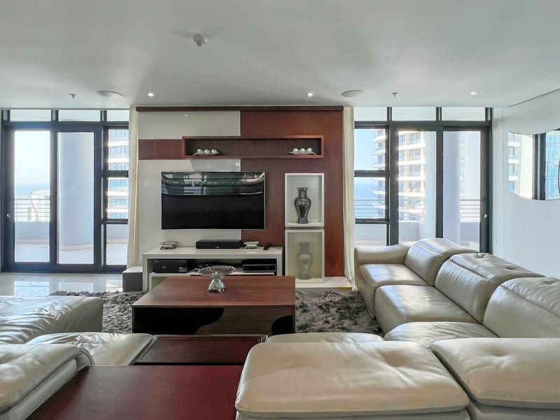 Spacious living room featuring floor-to-ceiling windows, integrated cabinetry, and recessed ceiling lighting, offering a bright and modern atmosphere.