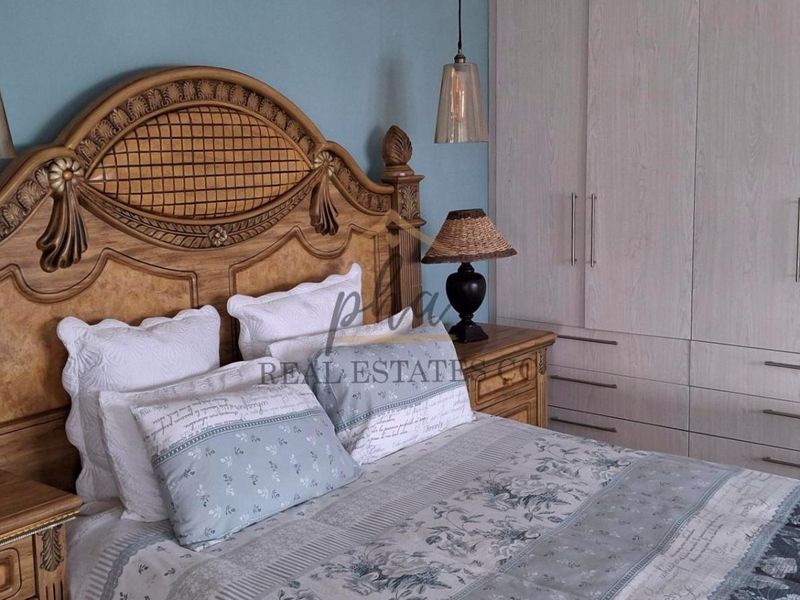 A well-maintained bedroom featuring built-in cupboards and decorative pendant lighting, offering a comfortable and functional living space.