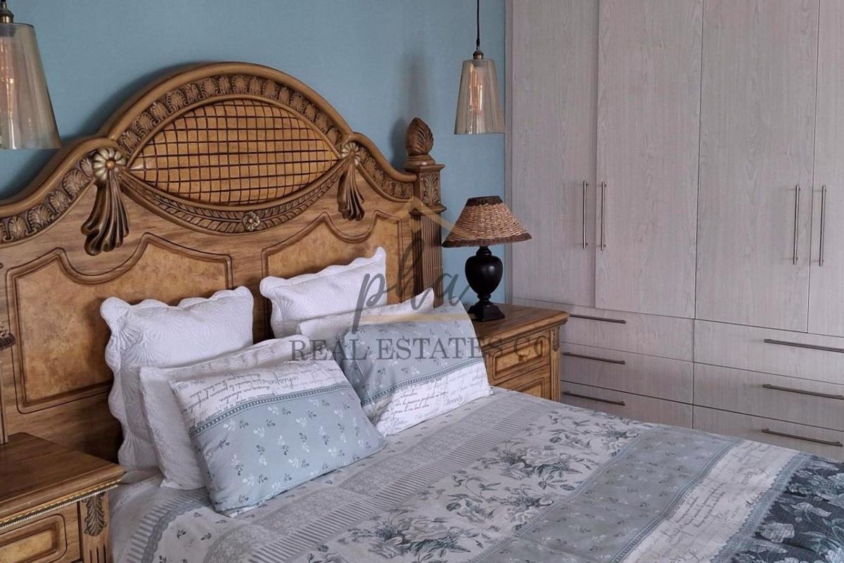 A well-maintained bedroom featuring built-in cupboards and decorative pendant lighting, offering a comfortable and functional living space.