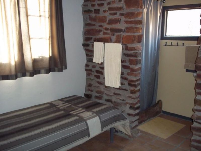 A bedroom featuring rustic exposed stone wall elements, tiled flooring, and an integrated shower area.