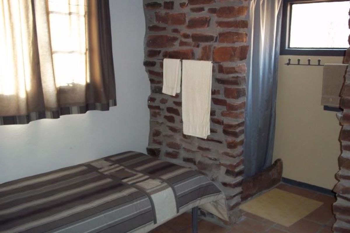 A bedroom featuring rustic exposed stone wall elements, tiled flooring, and an integrated shower area.