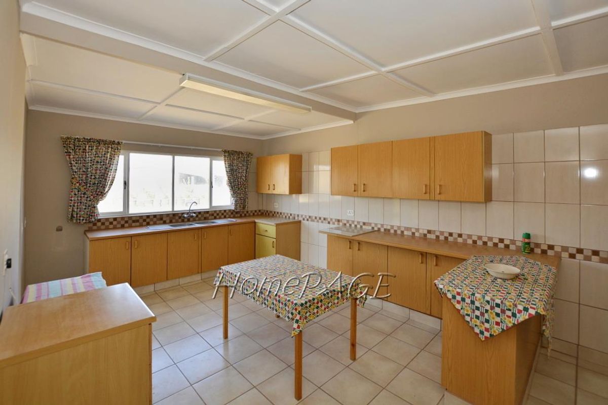 Spacious kitchen featuring light wood cabinetry, tiled countertops, and a functional layout with ample storage and workspace.
