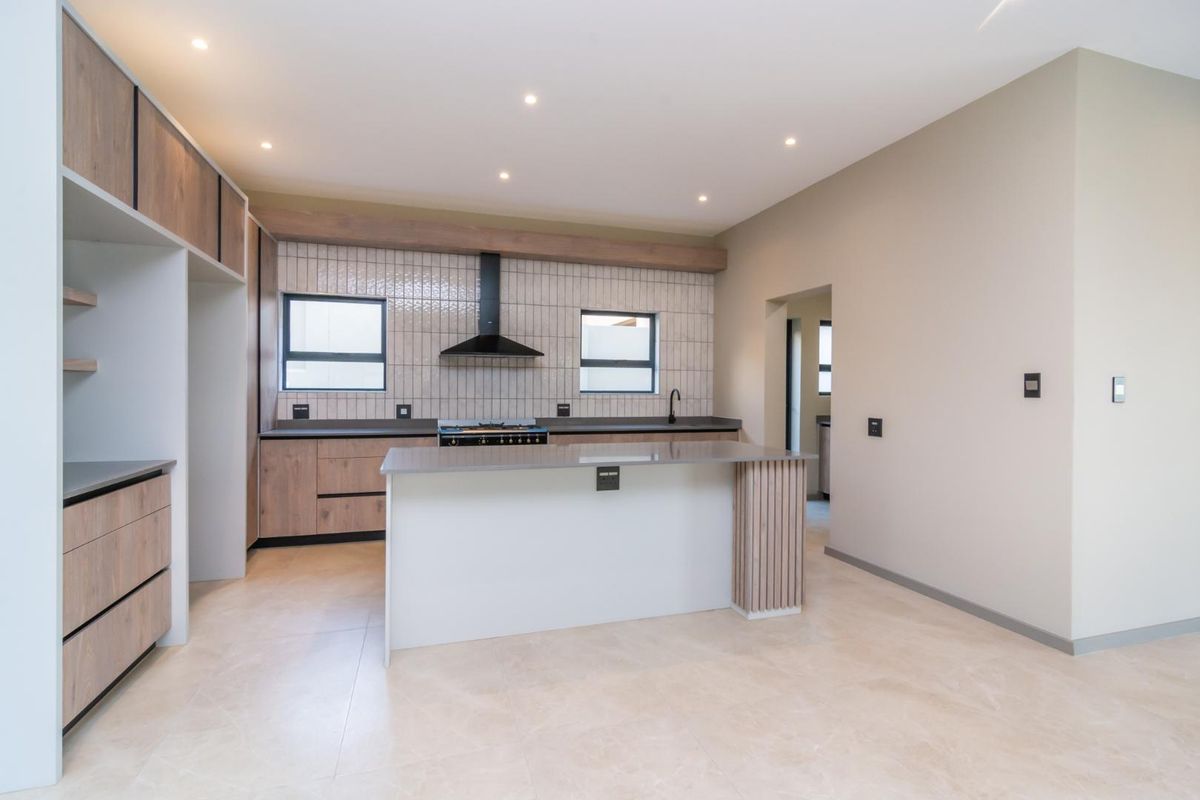Modern kitchen featuring a central island, wood-finish cabinetry, stone countertops, gas hob with extractor, and neutral tiled flooring in an open-plan layout.