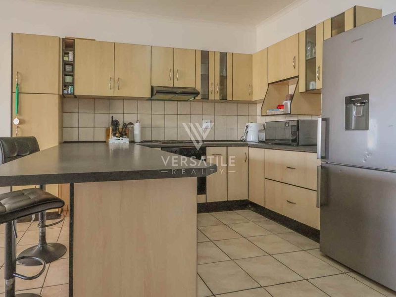 A functional kitchen featuring laminate cabinetry, tiled backsplash, and a breakfast bar, offering a practical layout for daily meal preparation.