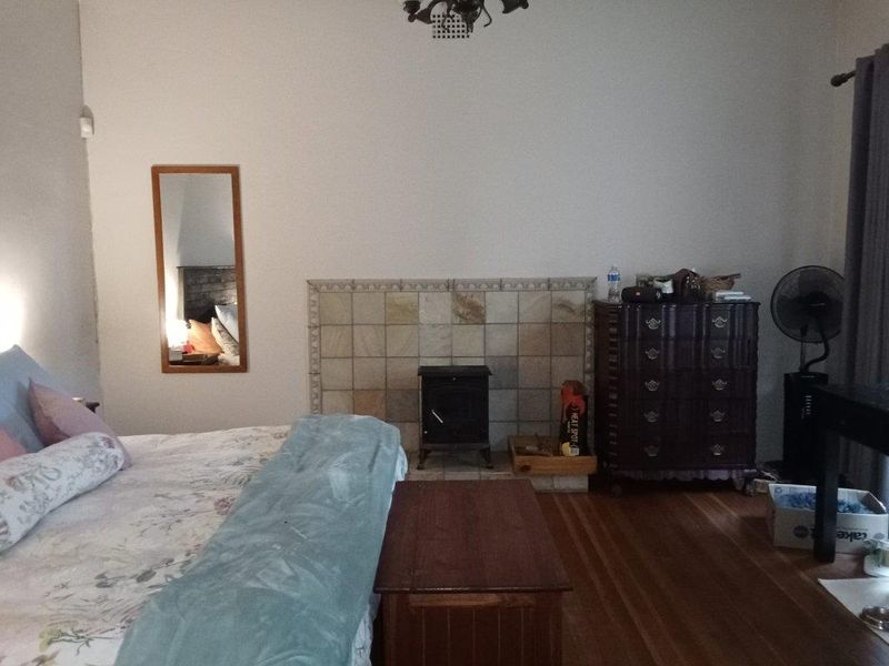 A bedroom featuring hardwood flooring and a central fireplace with a decorative tiled surround.