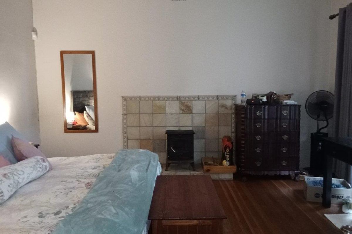 A bedroom featuring hardwood flooring and a central fireplace with a decorative tiled surround.