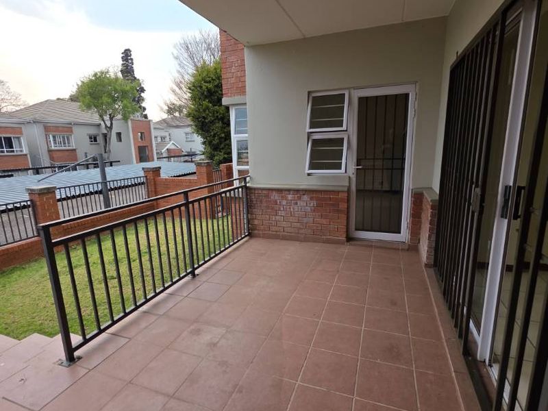 A covered balcony featuring tiled flooring, a metal balustrade, and direct access to the interior through sliding glass doors.