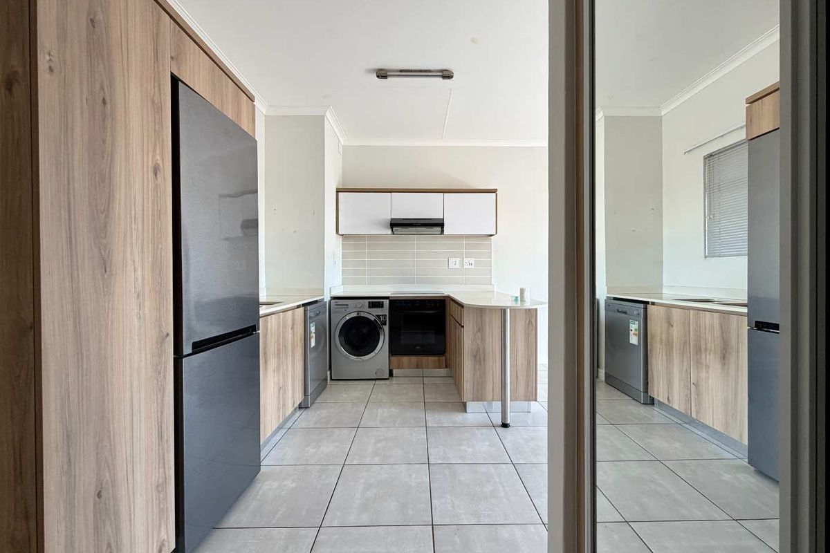 Modern kitchen featuring wood-look cabinetry, stone countertops, tiled flooring, and integrated appliance spaces, offering a clean and functional layout.
