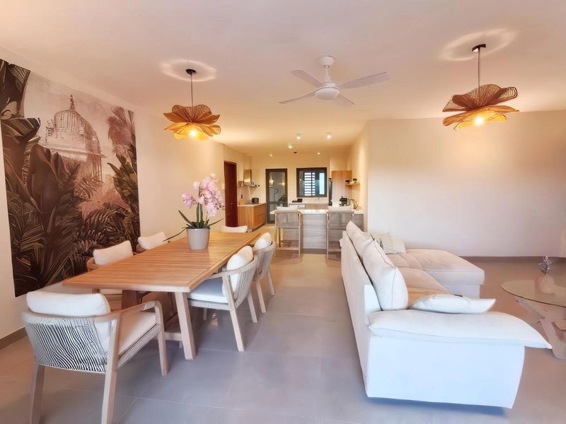 Spacious open-plan living and dining area featuring tiled floors, a central kitchen island, and modern ceiling fan, creating a bright and functional living space.