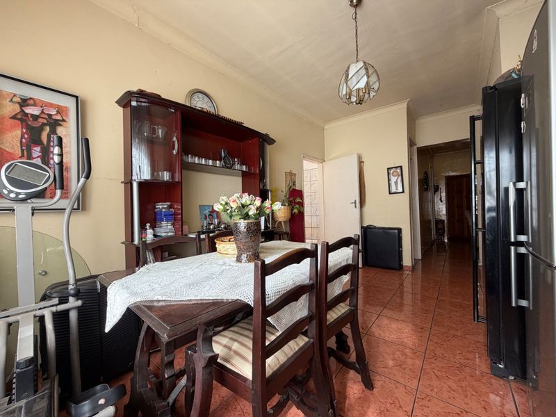 Dining area featuring tiled flooring and a pendant light fixture, showing signs of wear on the walls and ceiling.