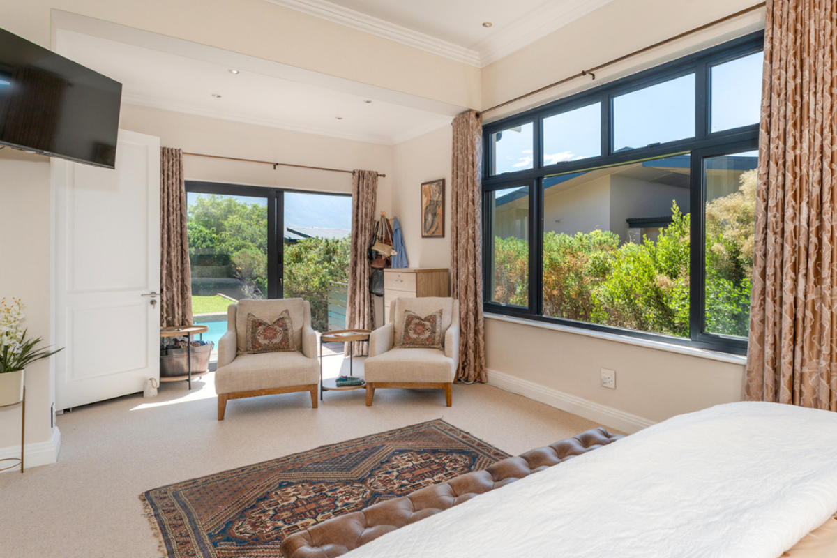 Spacious bedroom featuring large windows with garden views, recessed ceiling lighting, and direct access to an outdoor patio area.