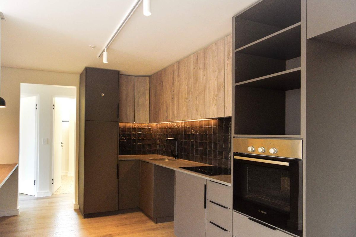 Modern kitchen featuring sleek cabinetry, built-in oven, hob, and stylish tiled backsplash with integrated under-cabinet lighting.