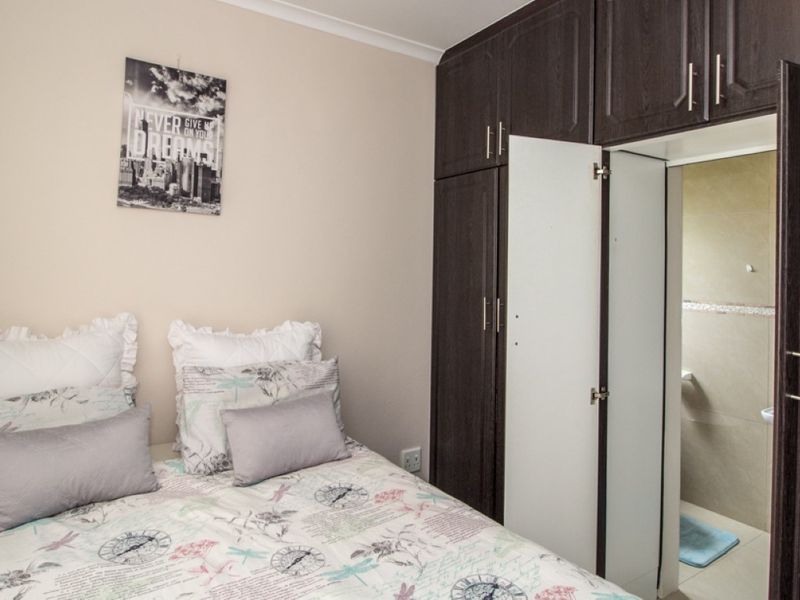 A bedroom featuring dark wood built-in cupboards and direct access to an en-suite bathroom.