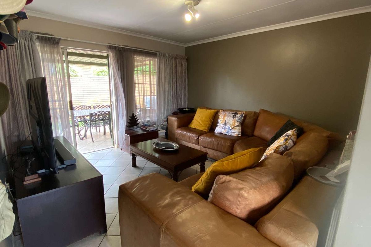 A comfortable living room featuring tiled flooring and large sliding glass doors that provide direct access to an outdoor patio area.