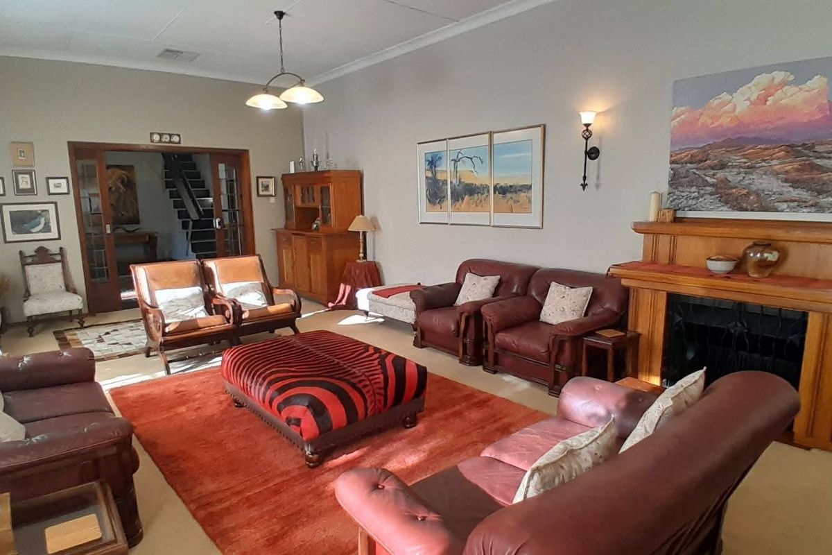 Spacious living room featuring a prominent wooden fireplace mantel, high ceilings, and double glass-paneled doors leading to an internal staircase.
