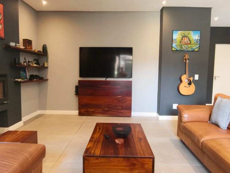 Modern living room featuring tiled flooring, a built-in fireplace, recessed lighting, and a neutral color palette with dark accent walls.