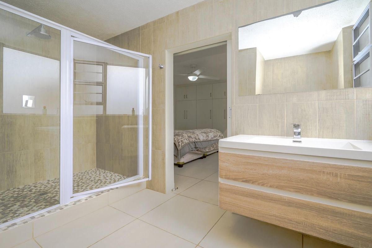 Modern bathroom featuring a walk-in shower with glass enclosure, wall-mounted vanity with basin, and neutral tiled finishes throughout.
