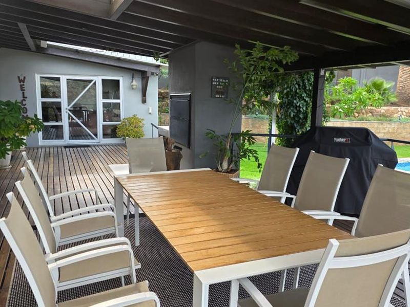 Spacious covered outdoor patio featuring timber decking, a built-in fireplace, and a skylight, perfect for alfresco dining and entertaining.