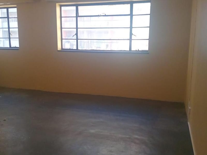 An empty bedroom featuring steel-framed windows and concrete flooring, offering a blank canvas for renovation and interior design updates.