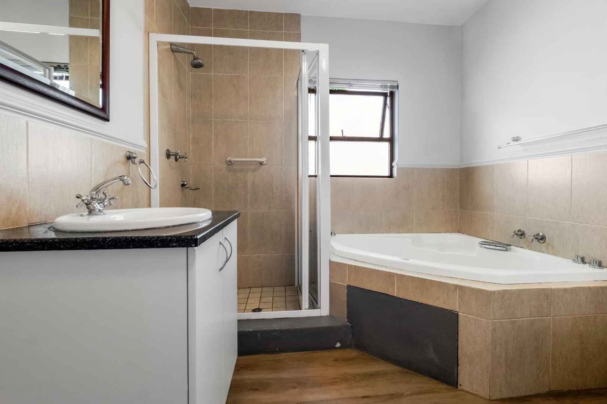 A functional bathroom featuring a corner bathtub, a separate glass-enclosed shower, and a vanity with a basin.