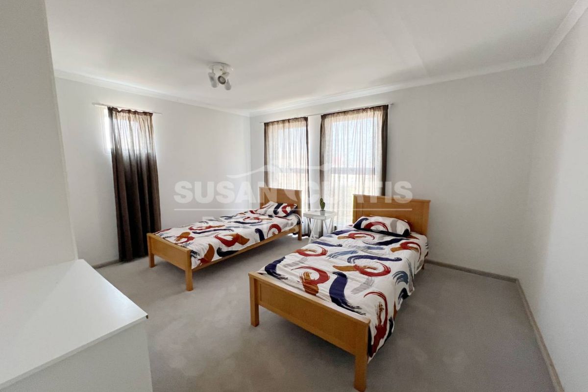 A spacious bedroom featuring neutral wall finishes, carpeted flooring, and large windows with installed curtain rods.