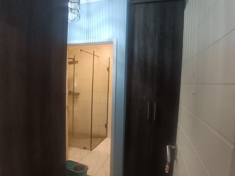 A bathroom featuring dark wood built-in cupboards and a glass-enclosed shower area with modern tiled flooring.