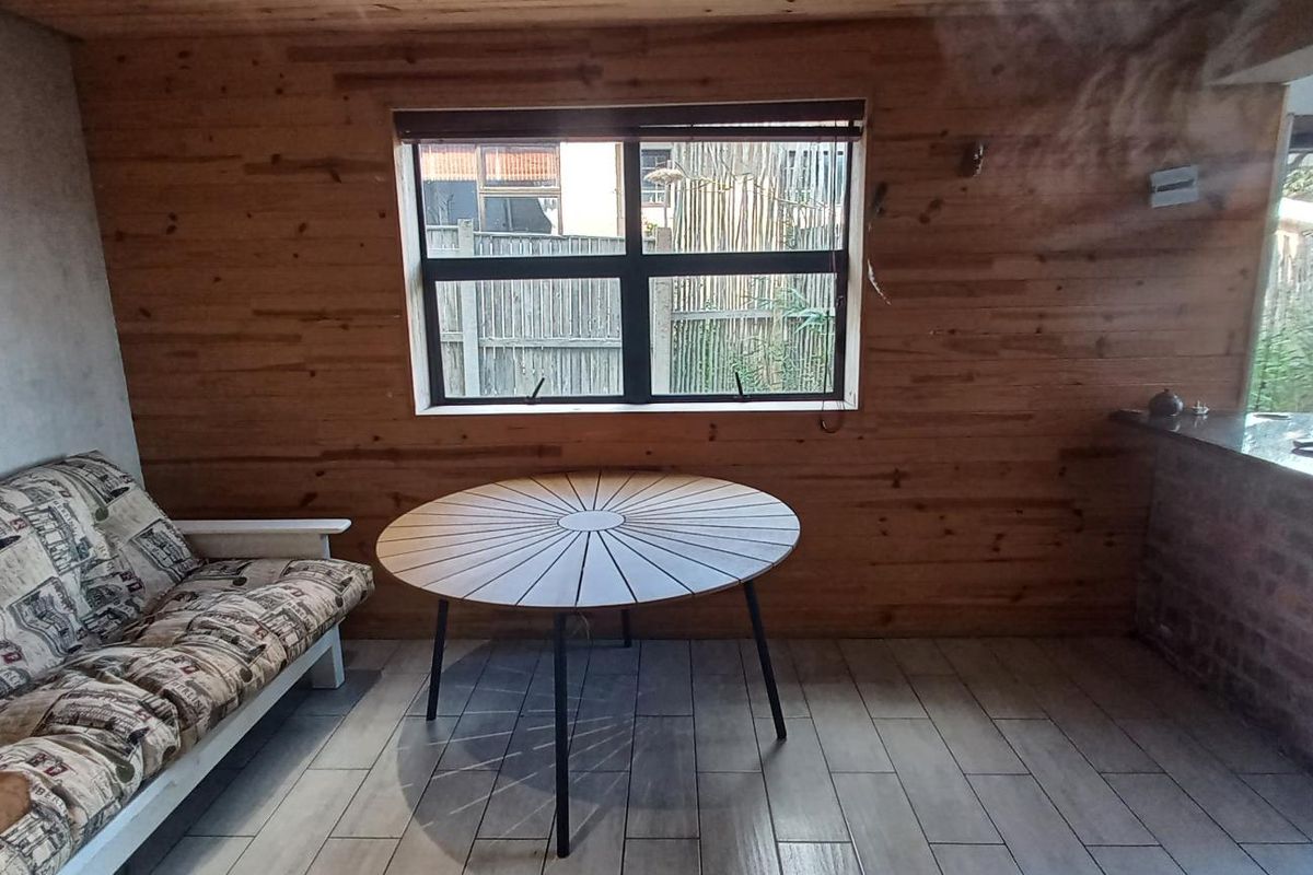 A rustic-style living area featuring wood-paneled walls, tiled flooring, and a built-in brick counter, offering a cozy and textured interior space.