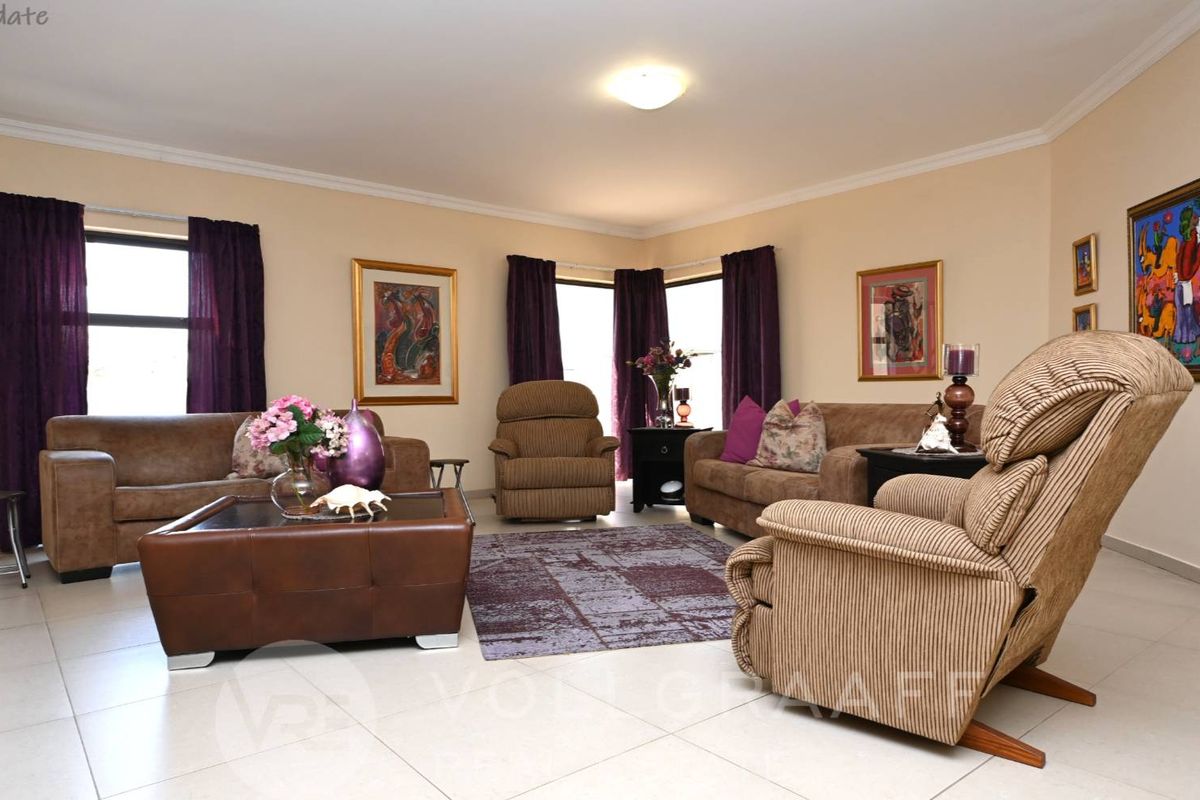 Spacious living room featuring large format floor tiles, neutral wall finishes, and a security gate leading to an outdoor area.