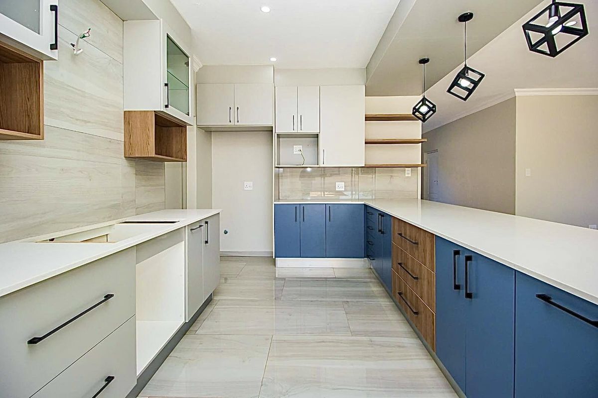 Modern kitchen featuring two-tone cabinetry, stone countertops, integrated shelving, and contemporary pendant lighting, offering a clean and functional culinary space.
