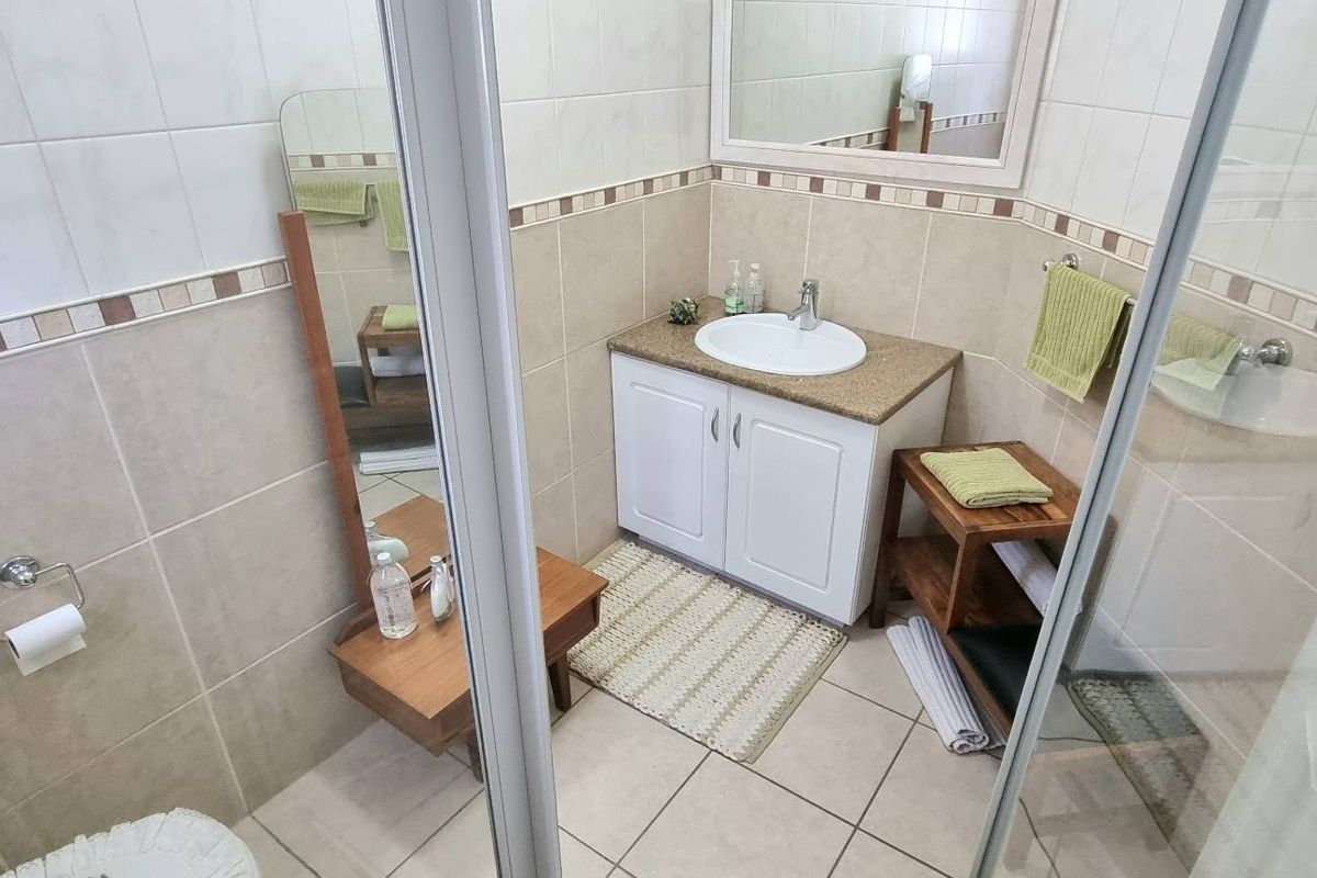 A functional bathroom featuring a vanity with a basin, tiled walls, and a shower enclosure.