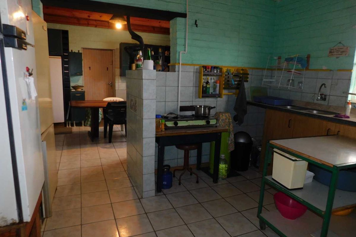 A functional kitchen area featuring tiled splashbacks, built-in cabinetry, and a tiled floor, with an open-plan layout connecting to the adjacent dining space.