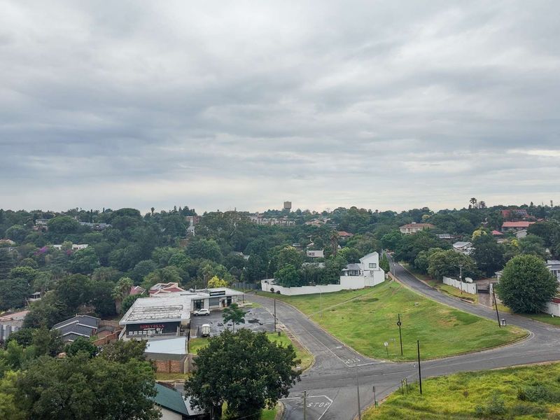 An elevated aerial view overlooking the surrounding suburban landscape, featuring green spaces, local roads, and residential properties under a cloudy sky.