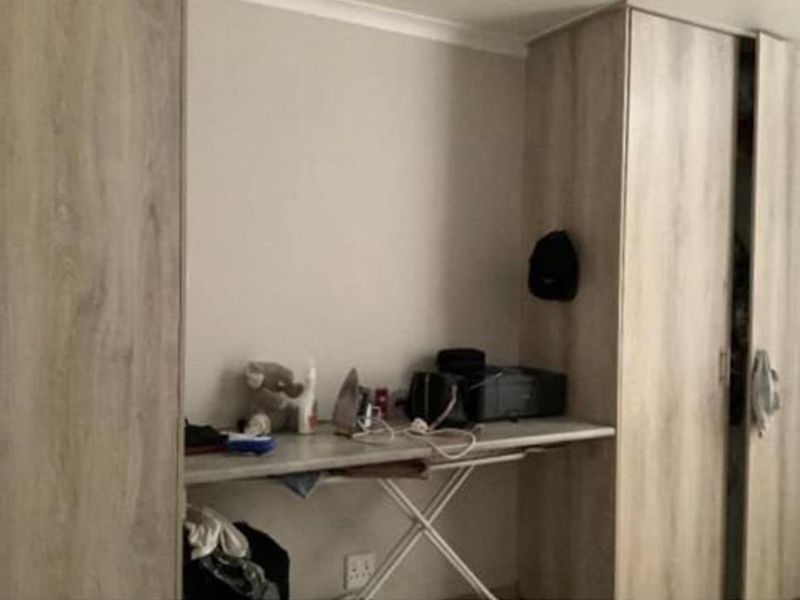 A bedroom featuring light wood-finish built-in cupboards and a matching integrated desk area.