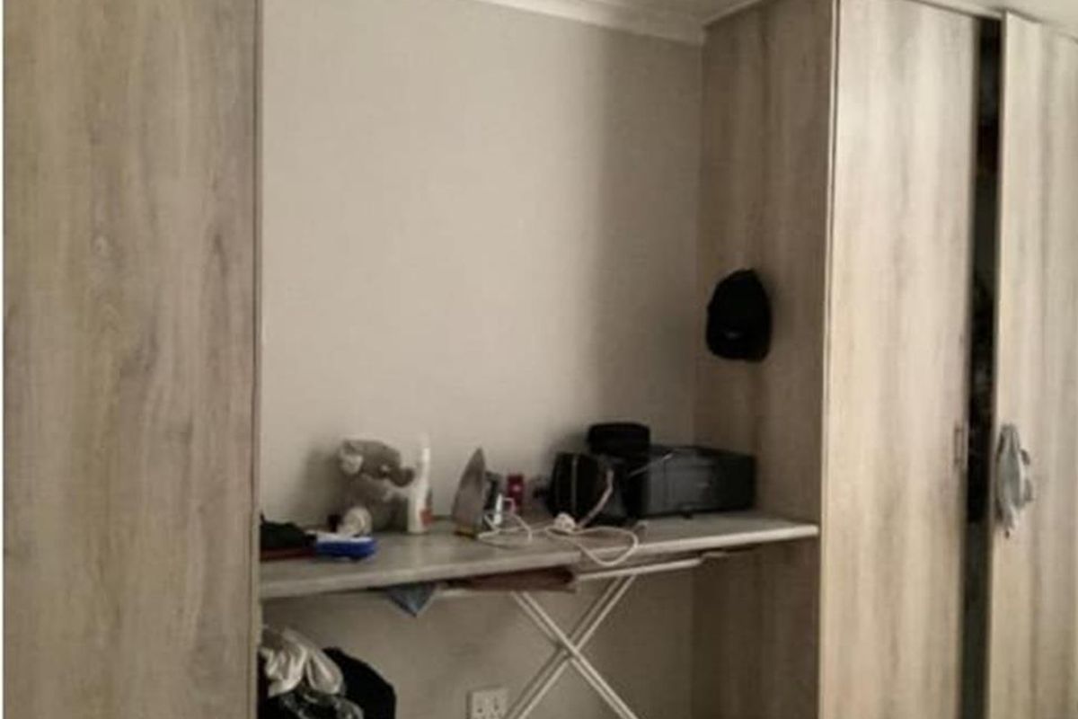 A bedroom featuring light wood-finish built-in cupboards and a matching integrated desk area.