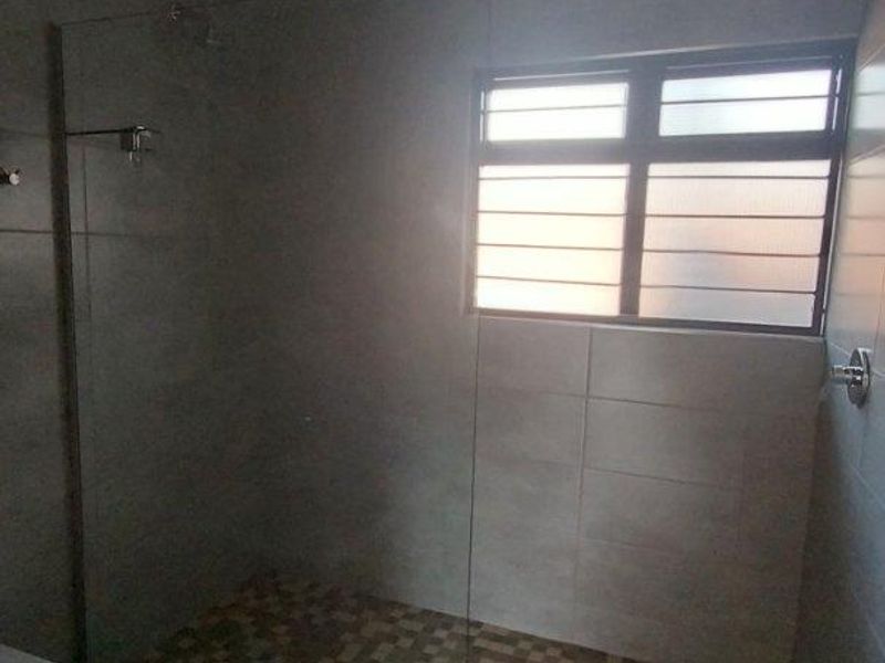 A modern bathroom featuring a walk-in shower with a glass screen, tiled flooring, and a bathtub, offering a clean and functional layout.
