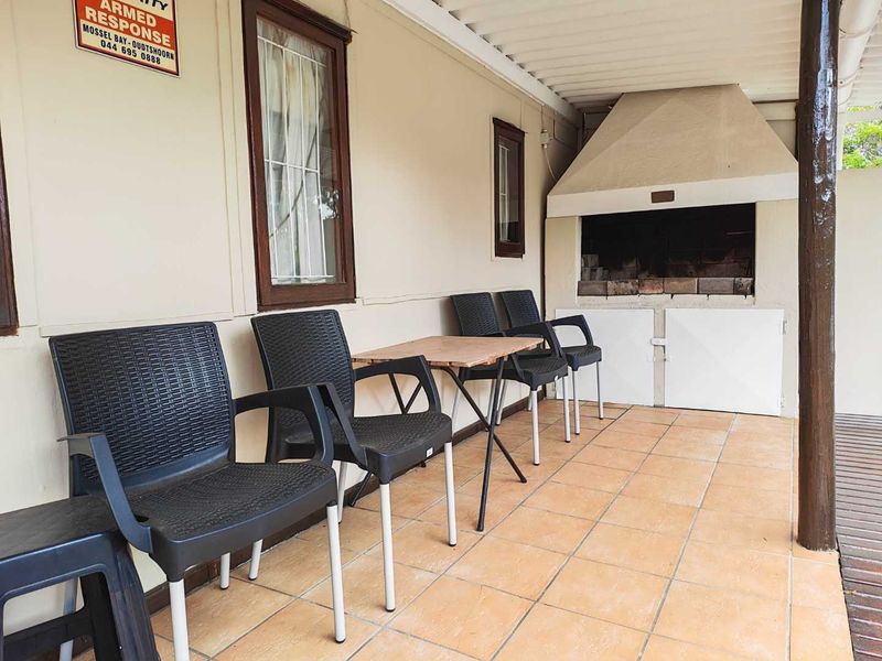 Covered patio area featuring a built-in braai and tiled flooring, providing a functional outdoor entertainment space.